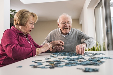 An elderly couple works on a puzzle.