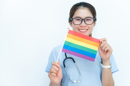 A healthcare professional displays a small Pride flag.