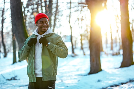 A man walks in the woods during winter.