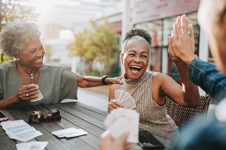Older adults play cards around a table.