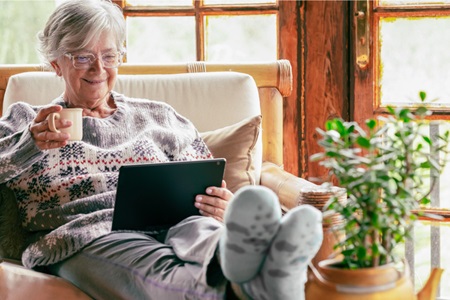 A woman enjoys a beverage while reading.