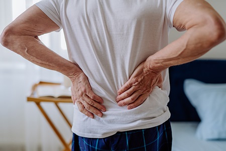 Senior man experiences back pain.