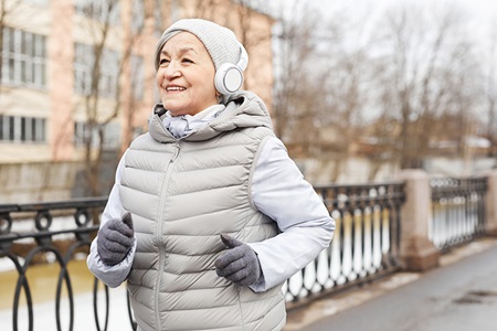 Senior woman running outdoors in winter.