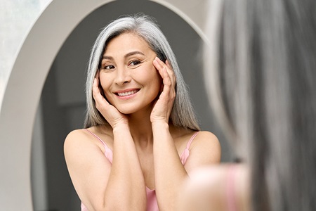A woman applies product as part of a skincare routine.