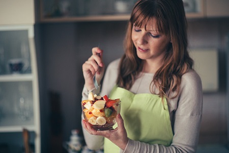 A woman eats a fruit salad.