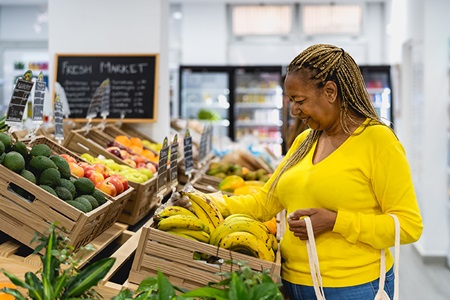 Woman picks up a banana in a grocery store